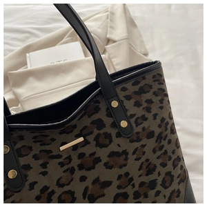 Detail of leopard print tote bag with golden metal plate and black leather handle