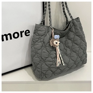Detail of grey quilted tote bag with heart stitching and cute plush mascot pendant