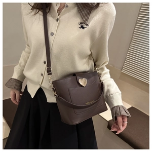 Detail of dark brown bucket bag featuring a gold heart buckle and lychee leather texture