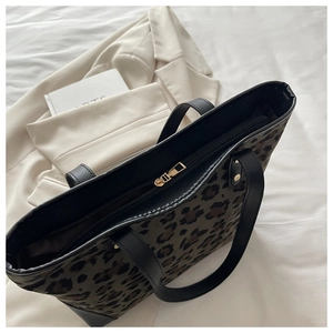 Close-up of leopard print tote bag with black leather straps and gold zipper detail