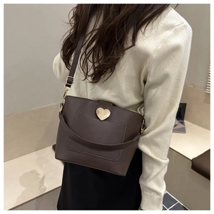 Gros plan d'un sac seau marron foncé avec une boucle en métal doré en forme de cœur