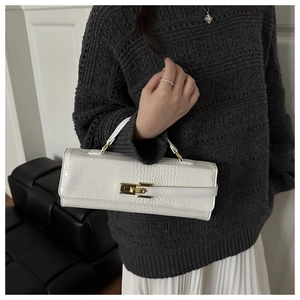 Close-up of white crocodile embossed leather handbag with elegant gold twist-lock closure