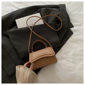 Close-up of caramel mini crossbody handbag with a stylish wavy flap design