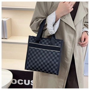 Detail of black tote bag featuring geometric cross patterns and durable canvas straps