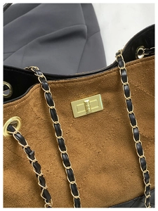 Detail of brown suede crossbody bag with gold chain strap and quilted rhombus pattern