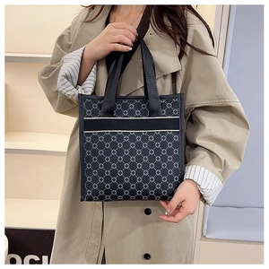 Detail of a black and white geometric tote bag with textured handles and clover pattern