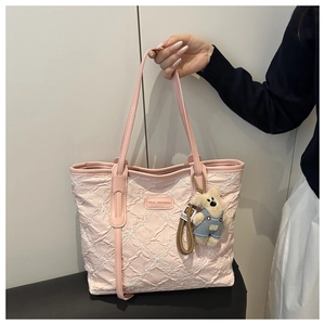 Detail of pink quilted tote bag with floral embroidery and cute bear plush charm