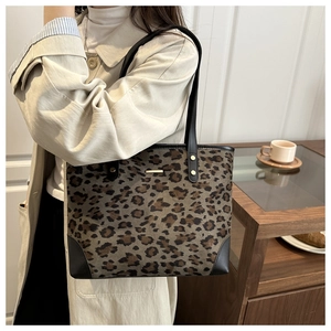 Detail of leopard print tote bag featuring gold hardware and black leather handles