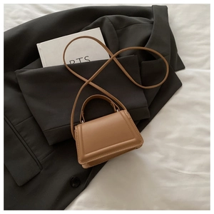 Detail showing brown mini crossbody bag with rectangular quilted stitching and handle