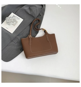 Detailed view of brown leather tote bag with white contrast stitching and metal buckle