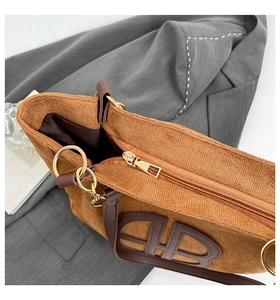 Détail du cabas en velours côtelé marron avec écusson logo en cuir et zip en métal