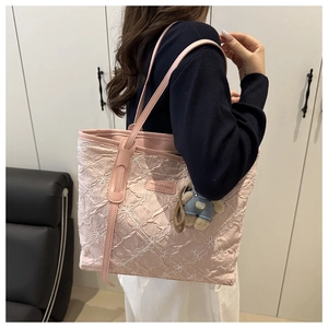 Pink quilted tote bag with floral embroidery and cute bear charm shown on a shoulder