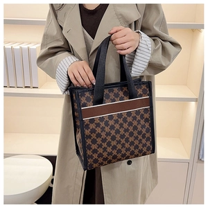 Detail of printed monogram tote bag with brown web strap and double top handles