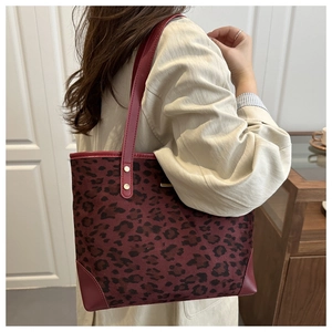 Detail showing the red leopard print tote bag with rivets and reinforced leather corners