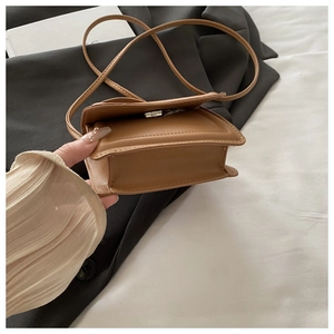 Detail view of a brown leather crossbody bag with silver magnetic snap and fine stitching