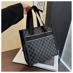 Detail of black tote bag with white floral patterns and sturdy shoulder straps