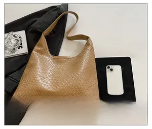 Detail of khaki woven hobo tote bag next to a tablet for size reference