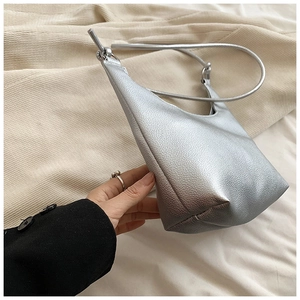 Détail du sac argenté montrant le grain de litchi et la poignée anneau minimaliste