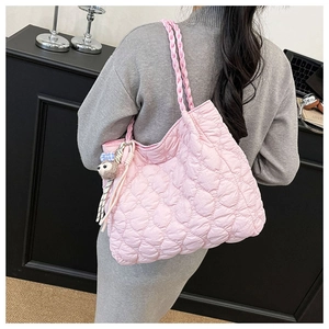 Detail of pink heart-quilted tote bag with woven straps and cute sloth charm accessory