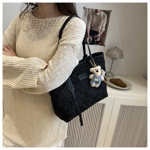 Detail of black sequined tote with pleated texture and a cute plush bear charm