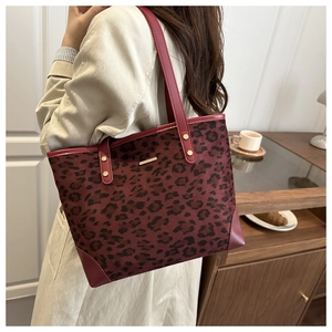 Detailed view of leopard print tote bag with red leather trim and gold metal hardware
