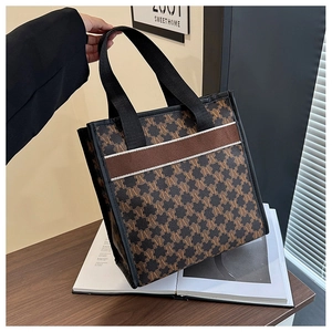 Detail of vintage monogram tote bag featuring brown M-pattern and striped handles