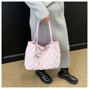 Pink quilted shoulder bag featuring a woven braided handle and cute cartoon character charm