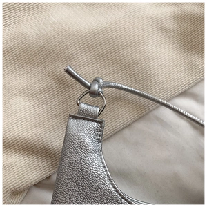 Détail du sac en cuir argenté texturé avec anneau en D et couture de la bandoulière fine