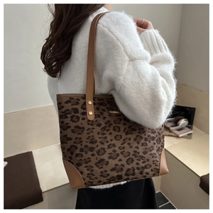 Brown leopard print tote bag with leather handles shown on a white knitted sweater