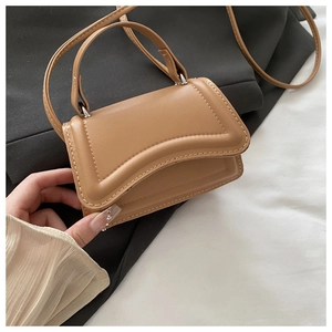 Detail of a brown micro handbag with a curved base and visible stitching accents