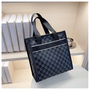 Macro detail of black tote bag featuring white cross pattern and functional front pocket