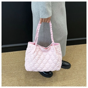 Detail of light pink quilted puff shoulder bag with woven handle for women