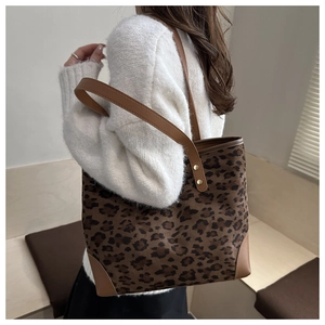 Detail of leopard print tote bag with brown leather straps and gold rivet accents