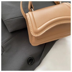 Detail of tan faux leather handbag with contrast white stitching and metal ring buckle