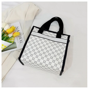 Detail view of large white canvas tote bag with black geometric cross pattern and straps