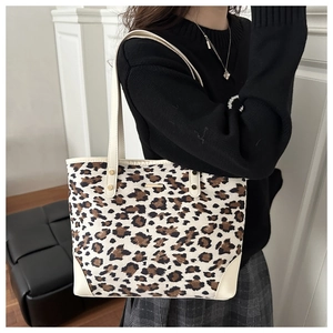 Detail of leopard print tote bag with cream leather trim and gold metal hardware accent