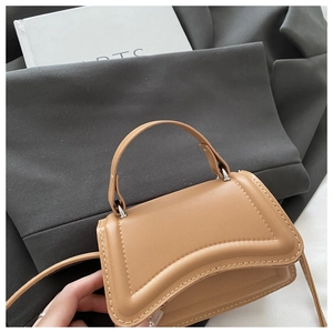 Close-up of khaki mini handbag with decorative stitching and curved wave flap design