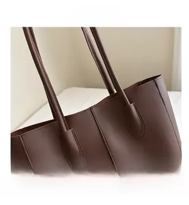 Détail macro des coutures renforcées sur les anses d'un sac cabas marron foncé