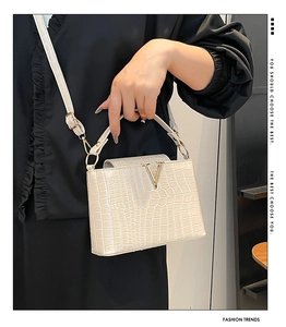 Detail of cream faux crocodile bucket bag with gold V hardware and adjustable strap