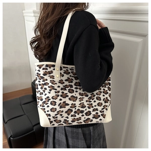 Detailed view of leopard print tote bag with white leather straps worn by a model