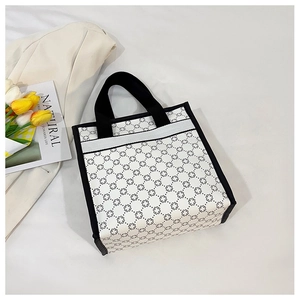 Detailed view of white tote bag with black geometric clover pattern and black handles