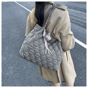 Detail of grey heart-quilted tote bag featuring a cute sheep plush charm and ribbon decor