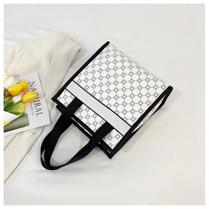 Detailed top view of a white canvas tote bag with geometric floral patterns and styling props