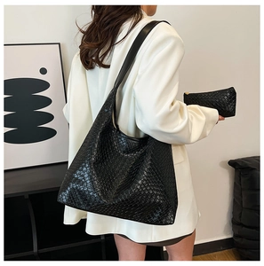Detail of black woven textured tote bag with matching zipper pouch on model