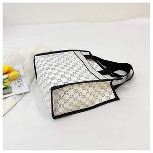 Detail of white tote bag with black floral dot pattern and reinforced handles