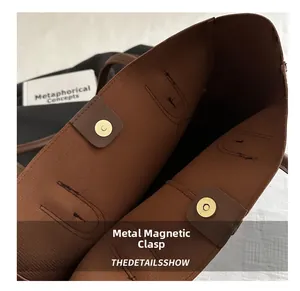 Détail de la fermeture à pression magnétique en métal doré d'un grand sac cabas marron