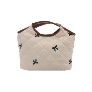 Quilted cream tote bag with black bow embroidery and dark brown leather top handles