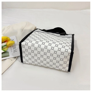 Detailed close-up of a square tote bag with black geometric patterns and faux leather handles