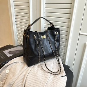 Quilted black leather tote with gold chain strap and square metal lock on a chair