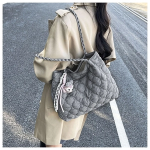 Detailed back view of a grey quilted tote bag with woven handles and plush charm detail